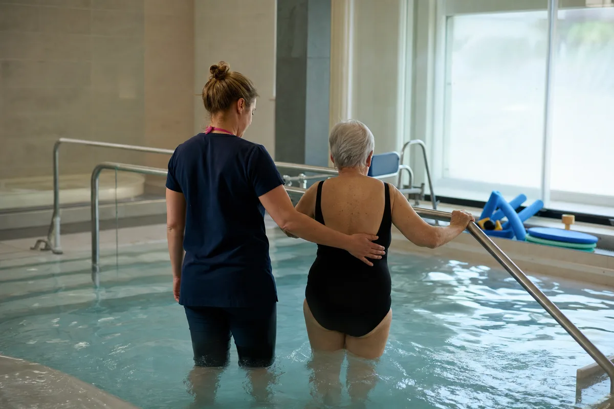 Aide-soignante et kinésithérapeute accompagnant un patient lors d&rsquo;une séance de rééducation